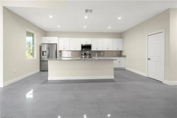 a view of kitchen with stainless steel appliances granite countertop a stove top oven a sink and a refrigerator