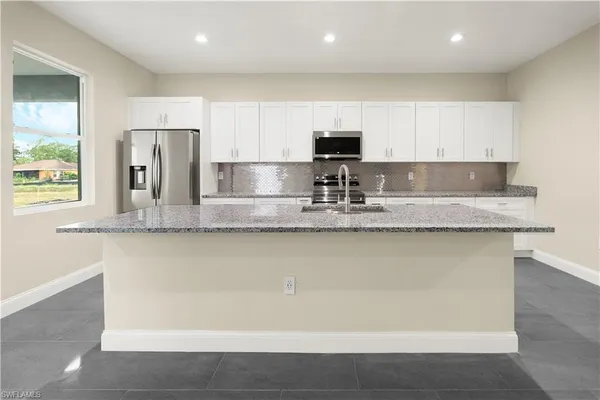 a kitchen with stainless steel appliances granite countertop a sink a refrigerator and a granite counter tops