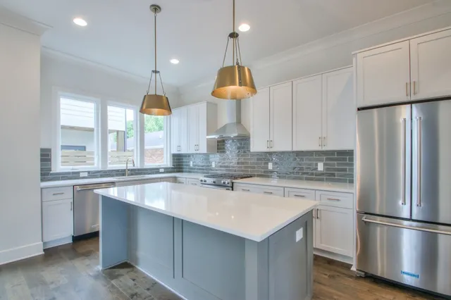 a kitchen with stainless steel appliances granite countertop a sink a stove a refrigerator and island with wooden floor