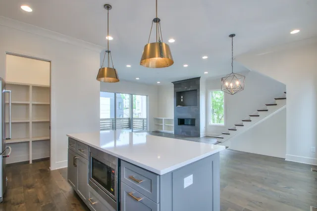 a kitchen with kitchen island granite countertop a stove a sink a center island and couches