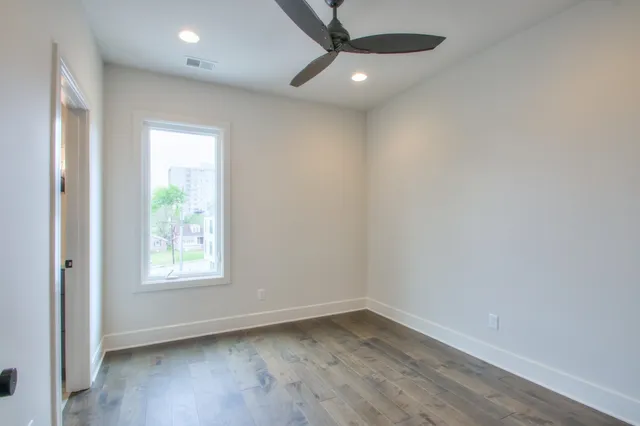 an empty room with wooden floor fan and windows