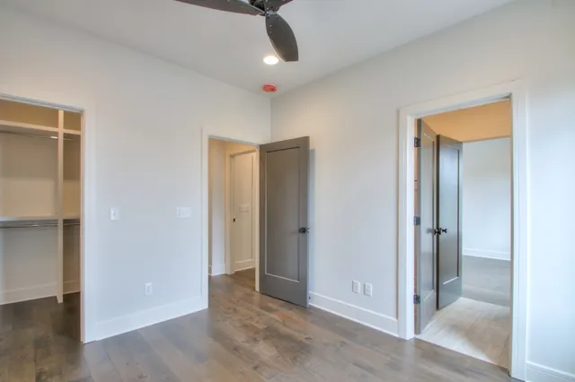 an empty room with wooden floor mirror and windows