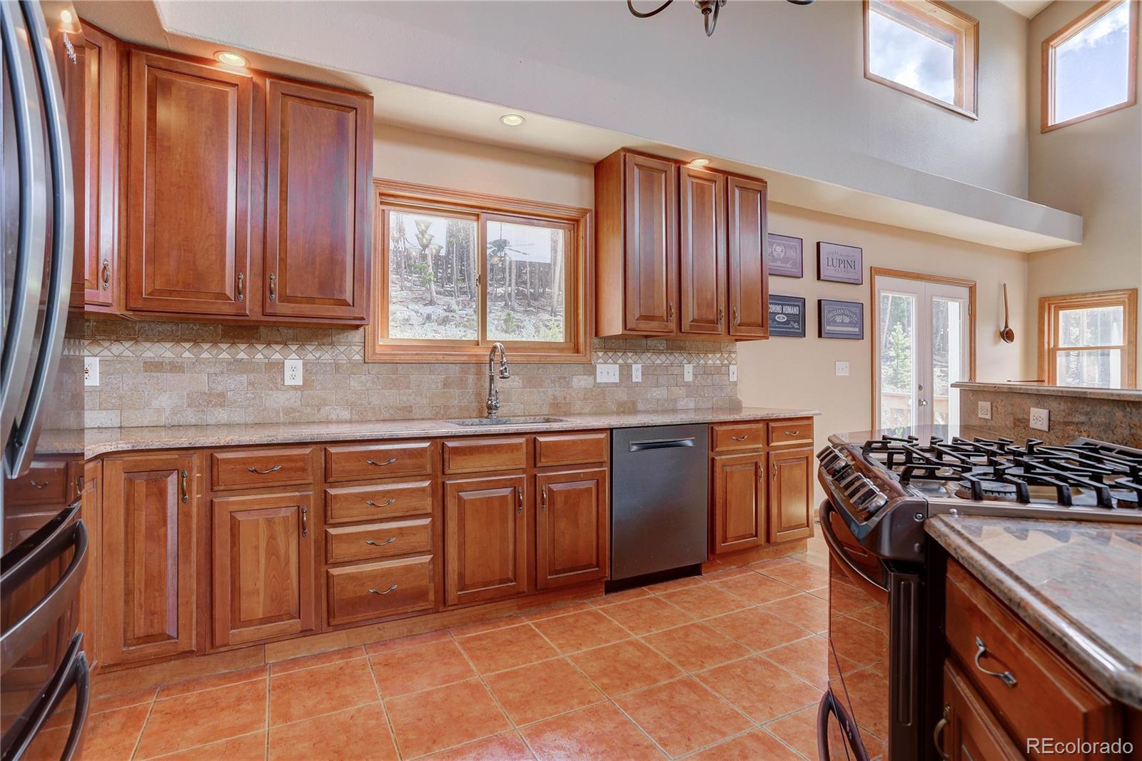 10922 Conifer Mountain Road Conifer, CO 80433 - Photo 11 of 37 a kitchen with stainless steel appliances granite countertop wooden cabinets a stove top oven a sink and dishwasher