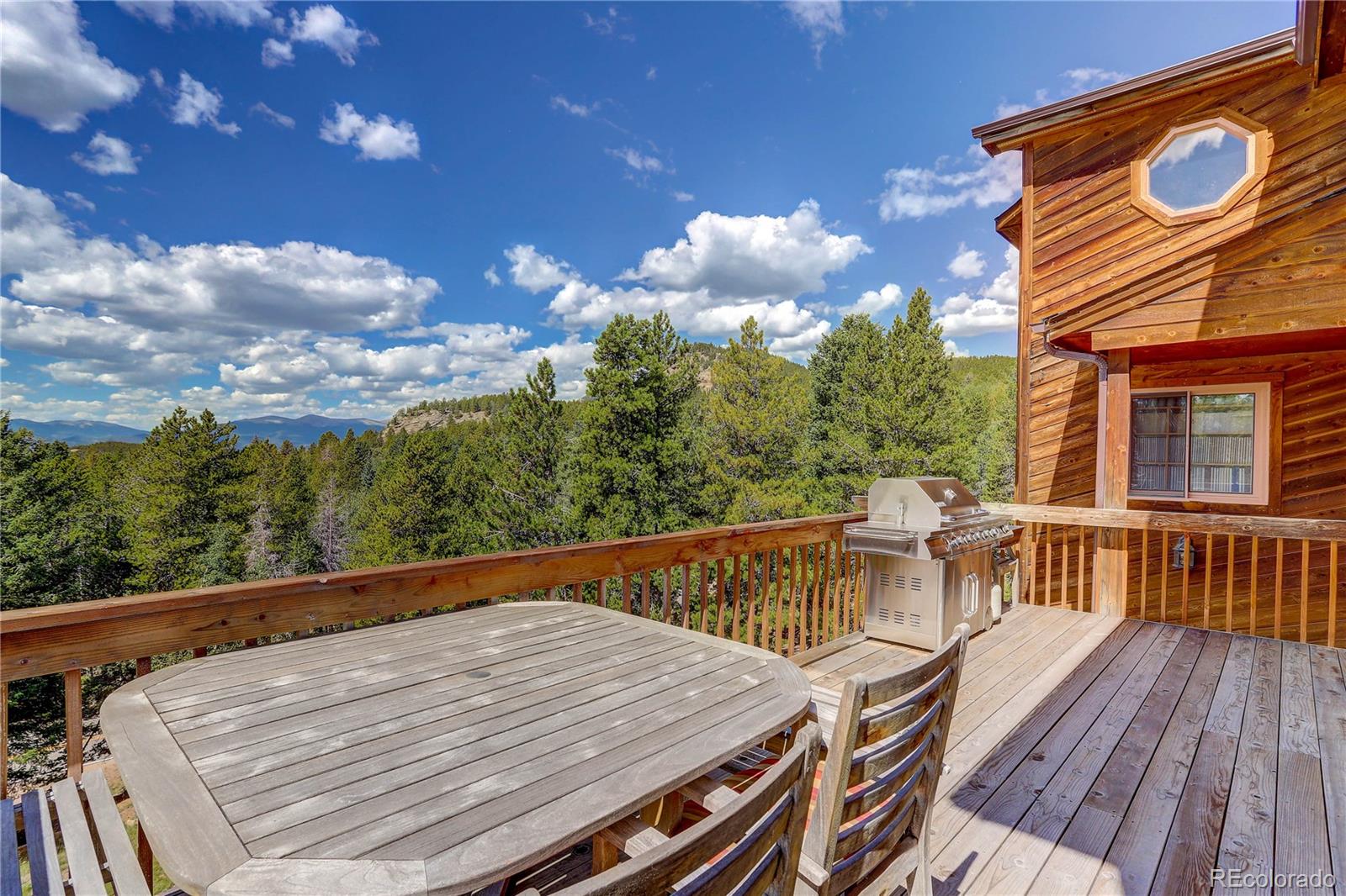 10922 Conifer Mountain Road Conifer, CO 80433 - Photo 12 of 37 a balcony with wooden floor and outdoor seating