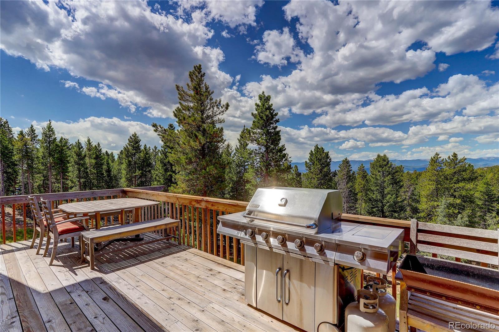 10922 Conifer Mountain Road Conifer, CO 80433 - Photo 13 of 37 a view of a roof deck with wooden floor and barbeque oven