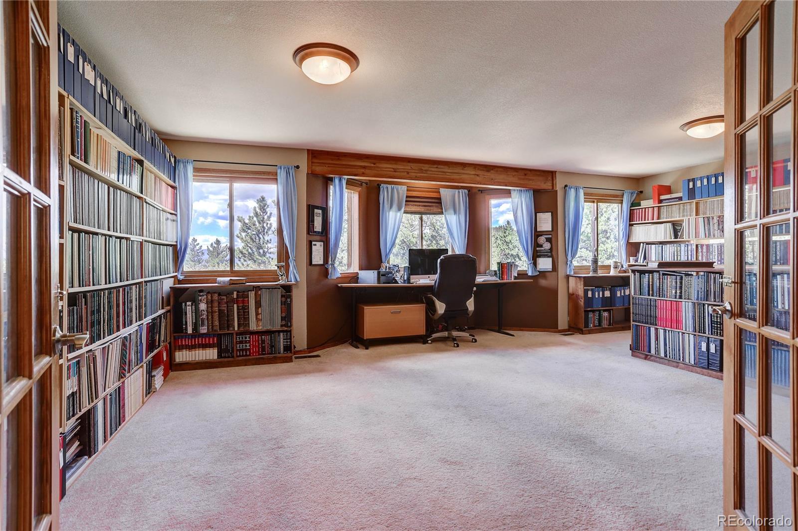 10922 Conifer Mountain Road Conifer, CO 80433 - Photo 15 of 37 a living room with lots of furniture and a book shelf