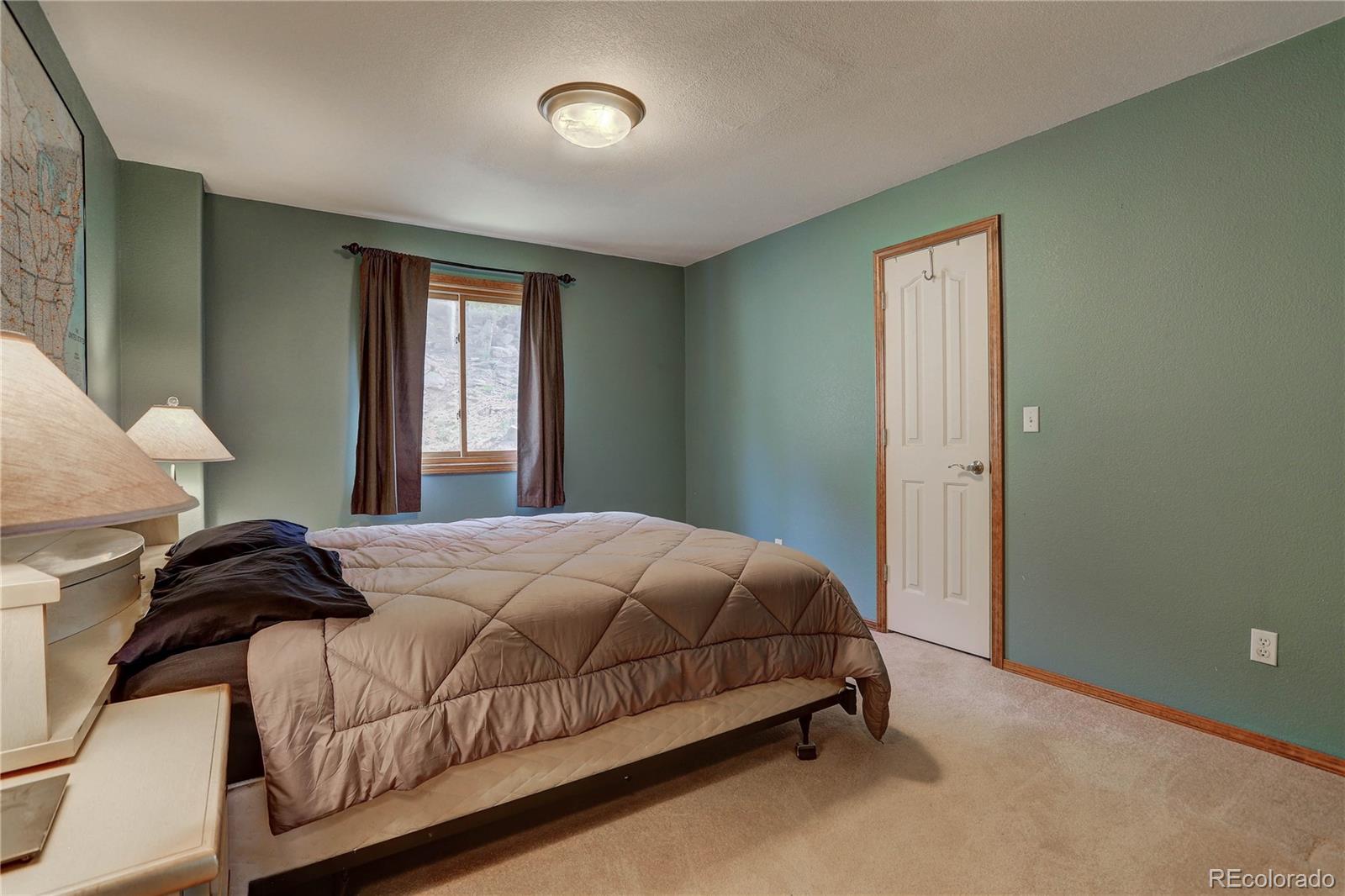 10922 Conifer Mountain Road Conifer, CO 80433 - Photo 17 of 37 a bedroom with a bed and window
