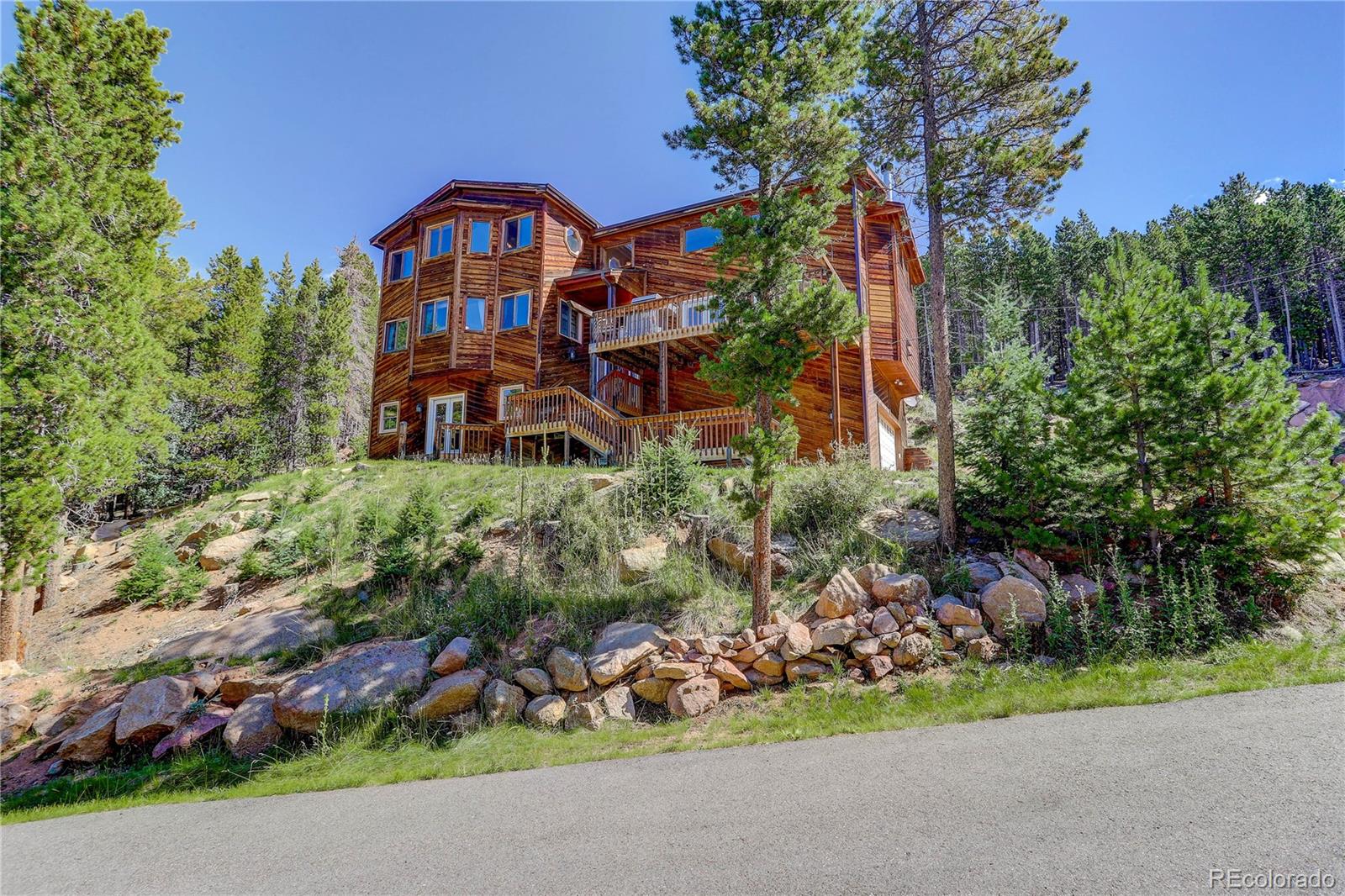 10922 Conifer Mountain Road Conifer, CO 80433 - Photo 2 of 37 an aerial view of a house with a yard and garden in the background