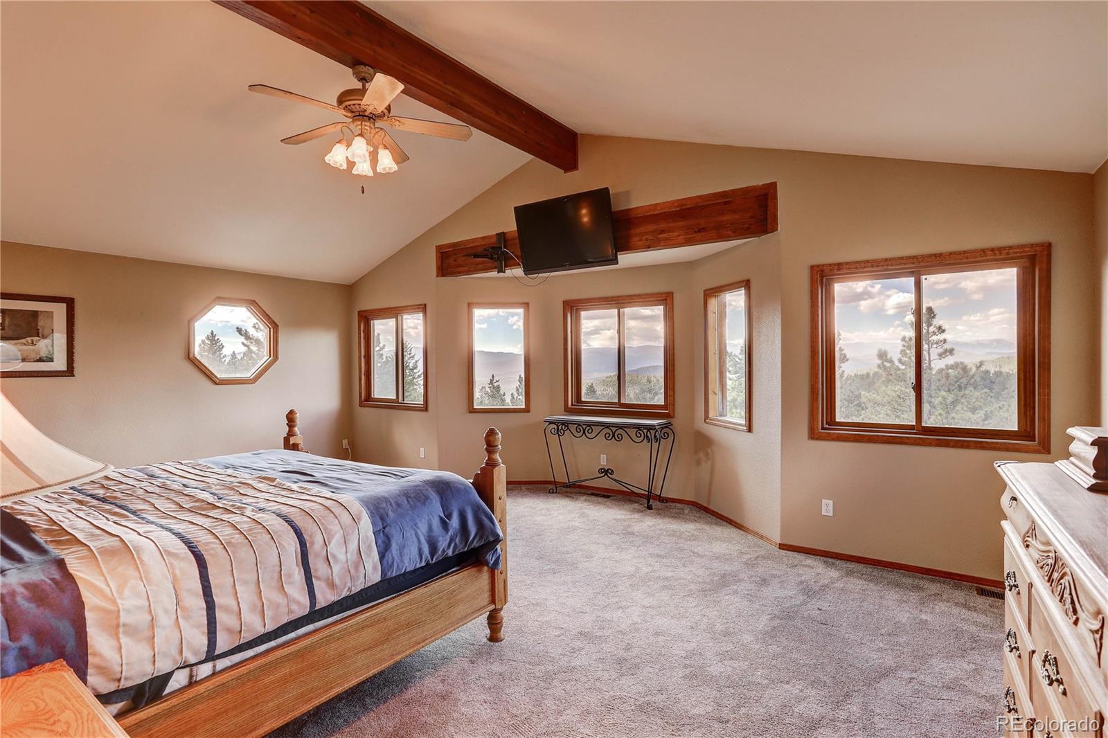 10922 Conifer Mountain Road Conifer, CO 80433 - Photo 21 of 37 a bedroom with a bed and a chandelier