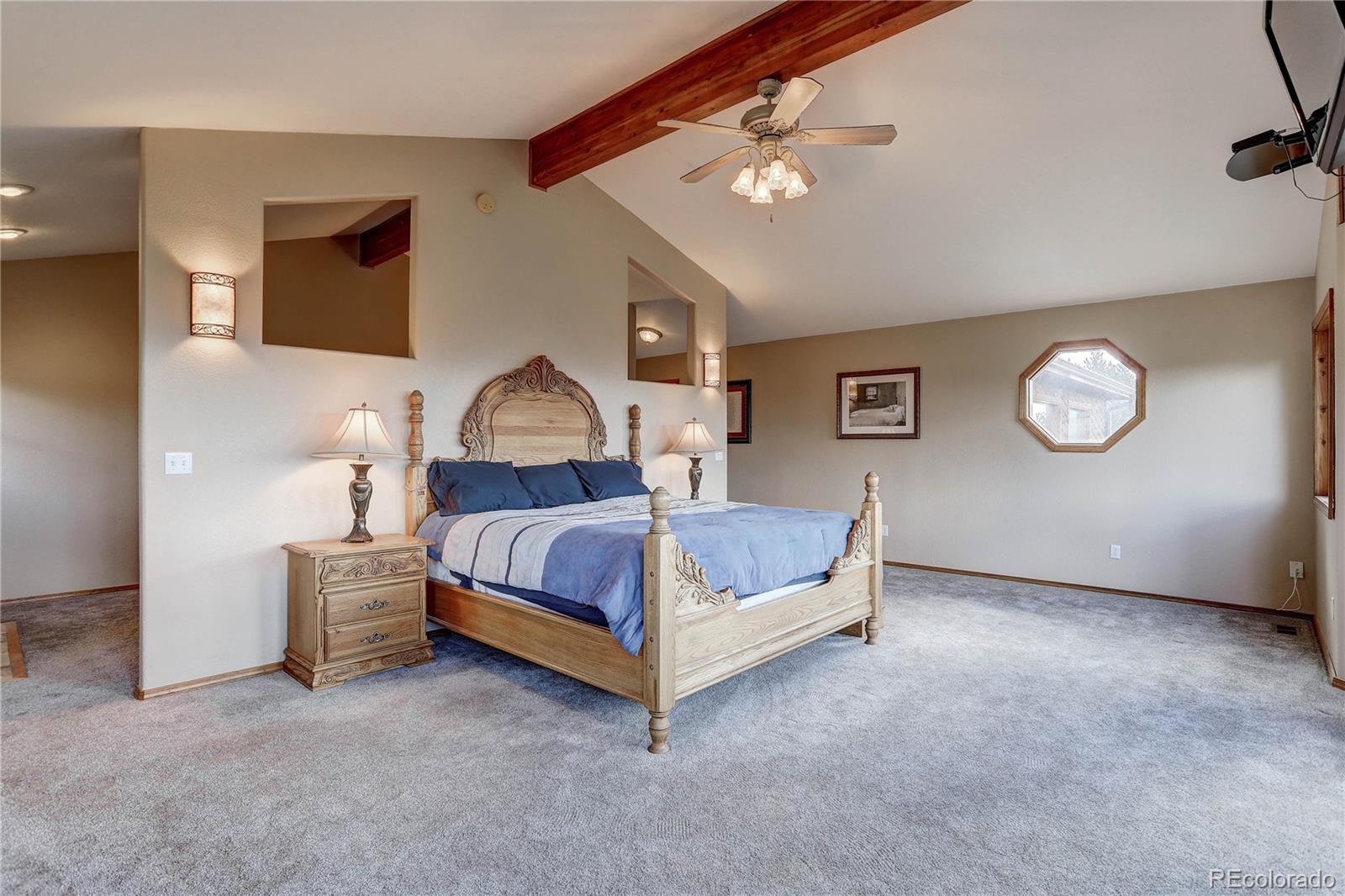 10922 Conifer Mountain Road Conifer, CO 80433 - Photo 23 of 37 a spacious bedroom with a bed and a lamp