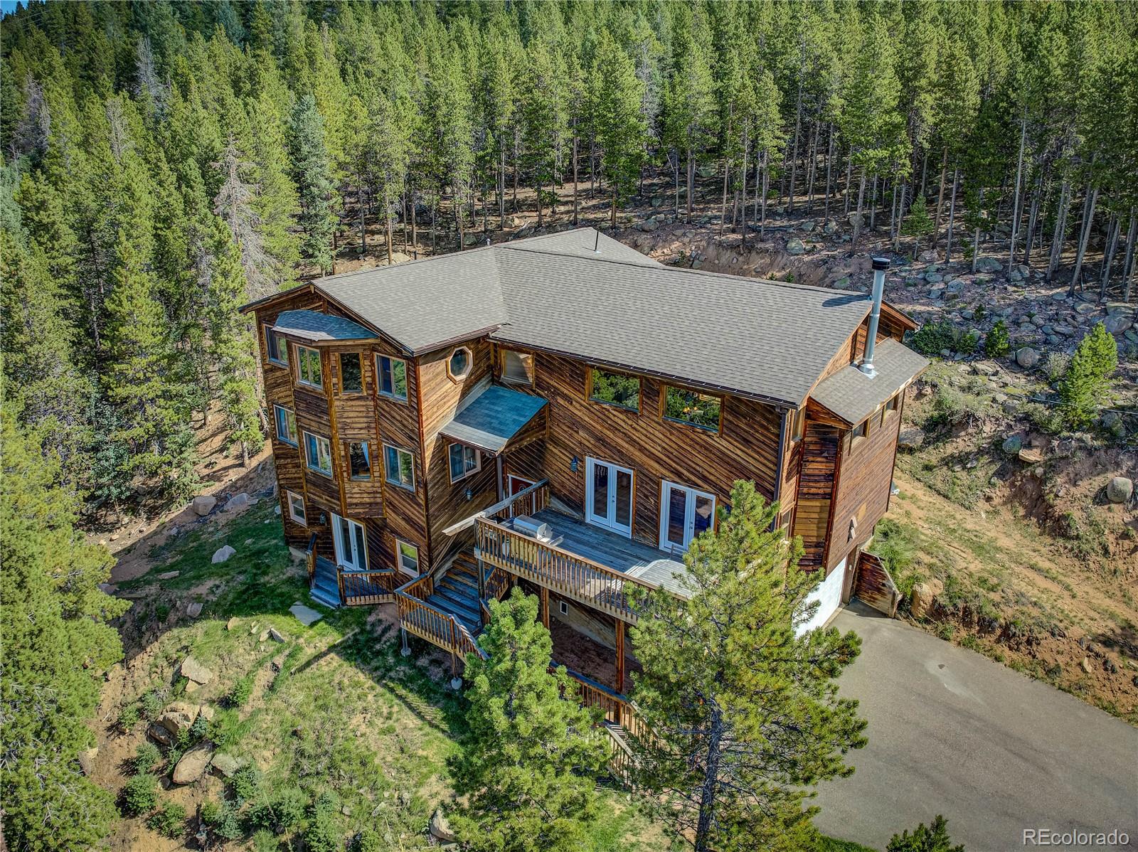 10922 Conifer Mountain Road Conifer, CO 80433 - Photo 37 of 37 an aerial view of a house with a big yard and large trees