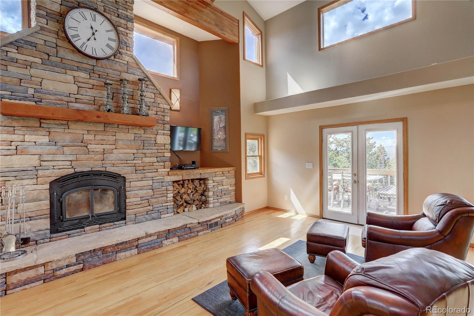 10922 Conifer Mountain Road Conifer, CO 80433 - Photo 5 of 37 a living room with furniture a fireplace a flat screen tv and floor to ceiling window