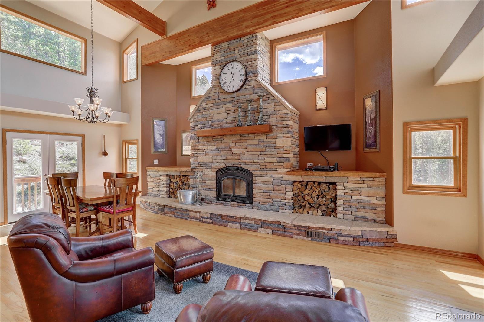 10922 Conifer Mountain Road Conifer, CO 80433 - Photo 8 of 37 a living room with furniture a fireplace and a flat screen tv