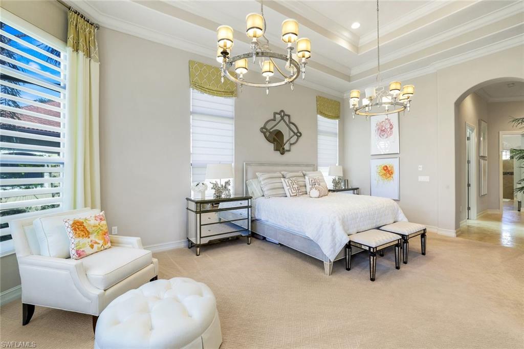 7304 Hagen Way Naples, FL 34113 - Photo 11 of 37 Carpeted bedroom with crown molding, an inviting chandelier, baseboards, a raised ceiling, and arched walkways