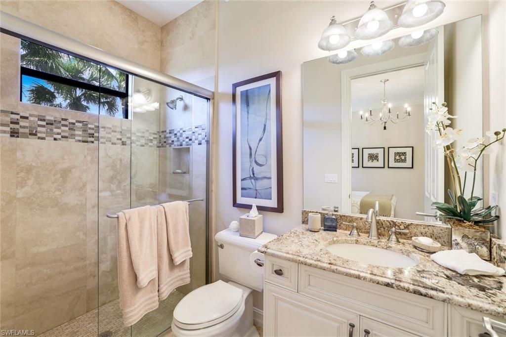 7304 Hagen Way Naples, FL 34113 - Photo 18 of 37 Bathroom featuring a stall shower, toilet, vanity, and a chandelier