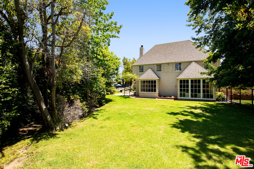 300 South Rockingham Avenue Los Angeles, CA 90049 - Photo 39 of 49 a view of a backyard with table and chairs potted plants and large tree
