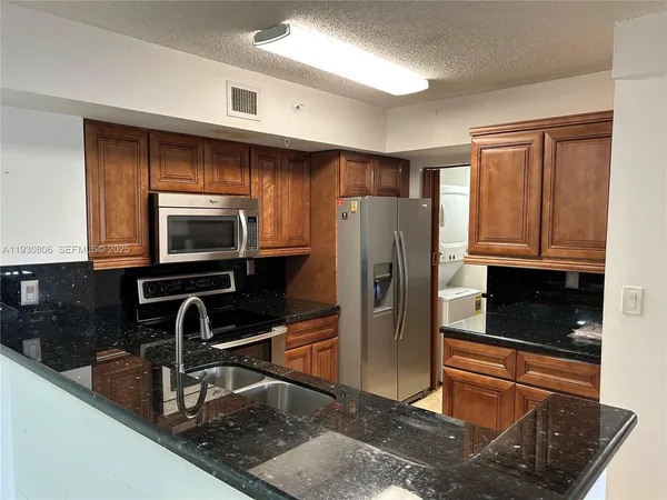 a kitchen with granite countertop a refrigerator and a sink