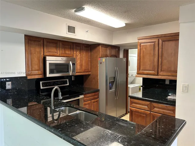 a kitchen with granite countertop a refrigerator and a sink
