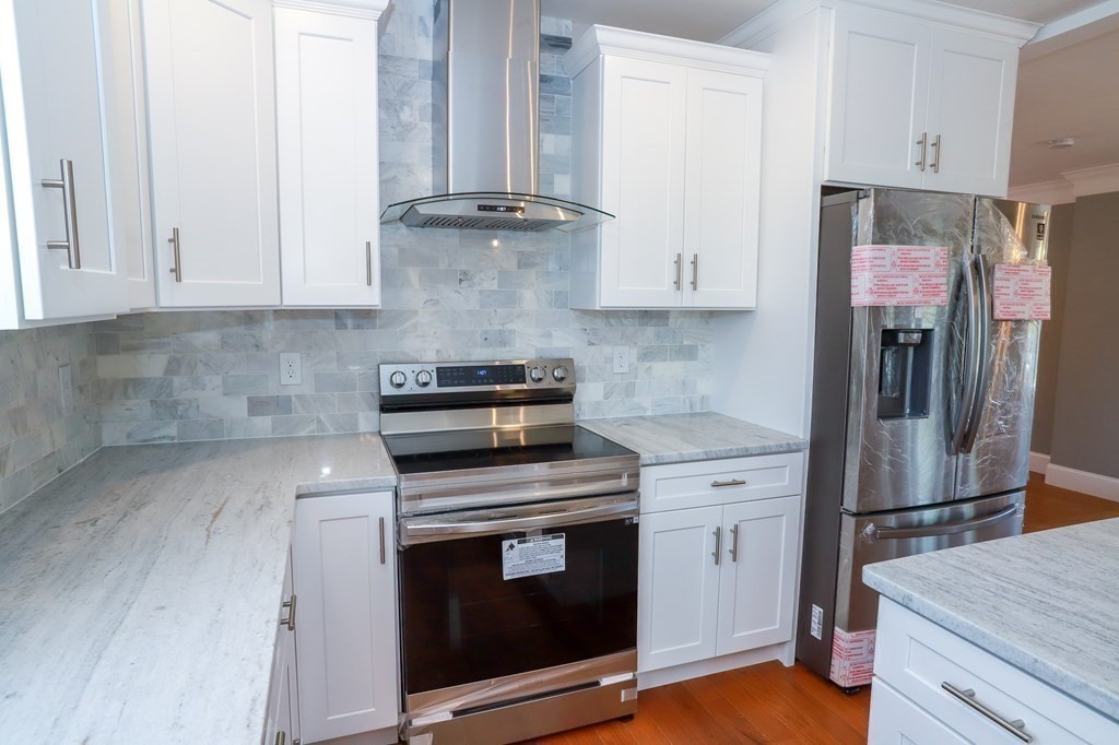 7 Ayer Road Littleton, MA 01460 - Photo 9 of 39 a kitchen with stainless steel appliances granite countertop a stove a refrigerator and white cabinets