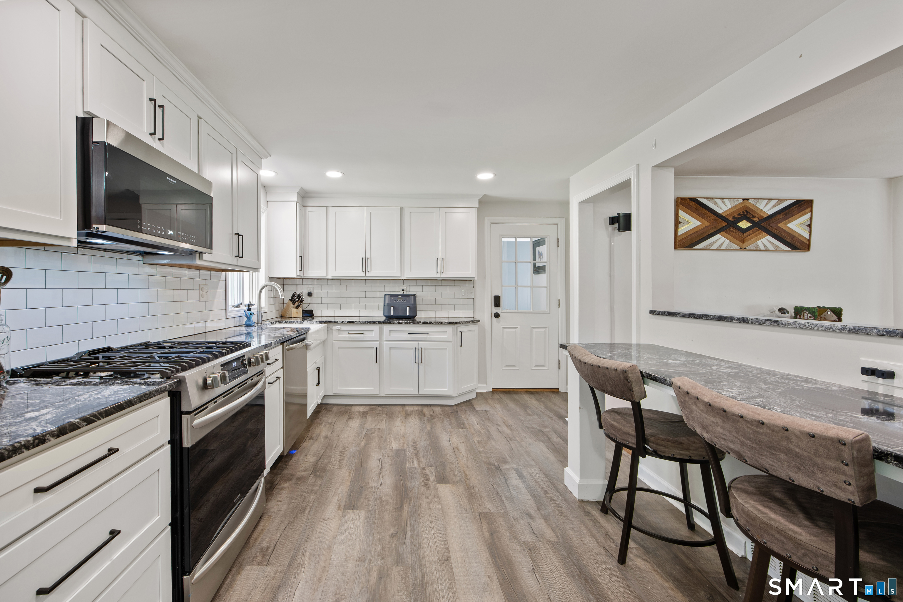 39 Grove Road North Haven, CT 06473 - Photo 8 of 38 a kitchen with stainless steel appliances granite countertop a stove top oven a sink dishwasher a dining table and chairs with wooden floor
