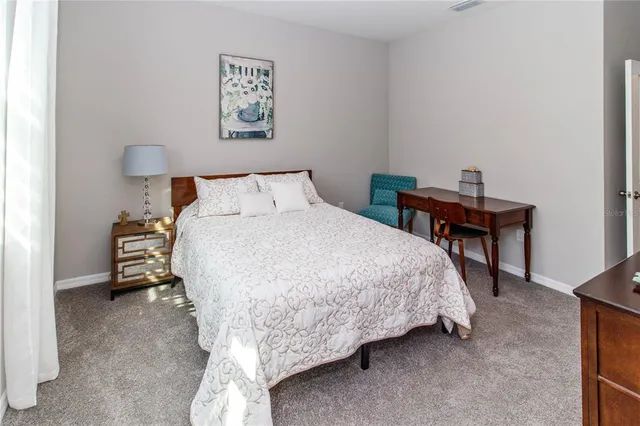 a bed sitting in a bedroom and table chair