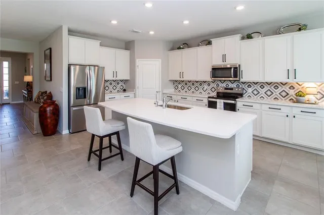 a kitchen with a dining table chairs refrigerator and microwave