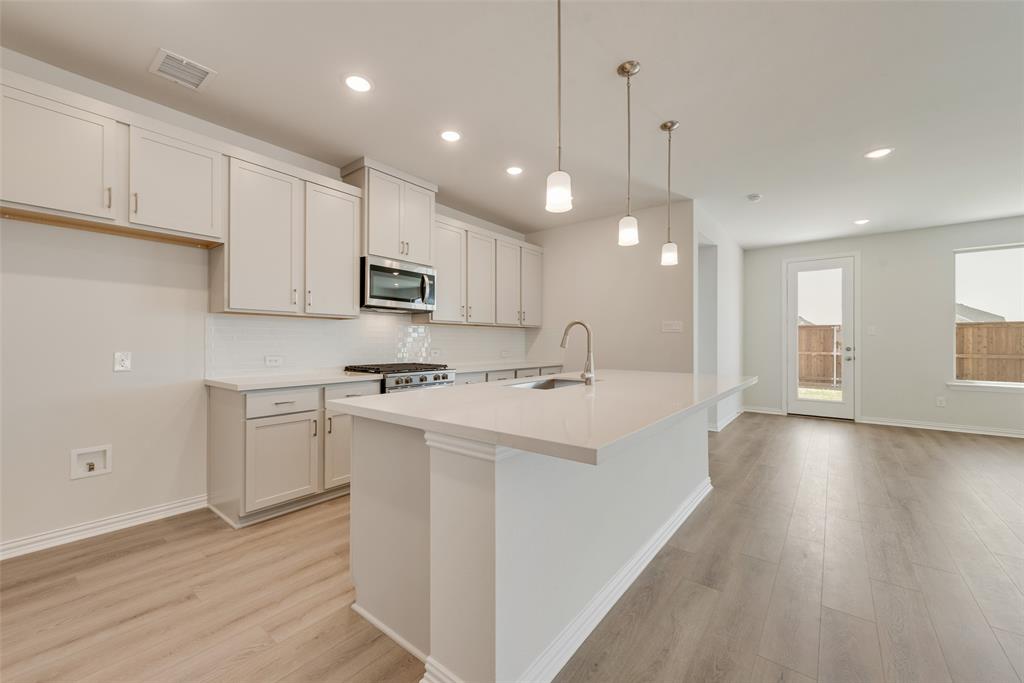 4136 Tarlton Road Little Elm, TX 75068 - Photo 5 of 28 a kitchen with kitchen island a sink stainless steel appliances and cabinets