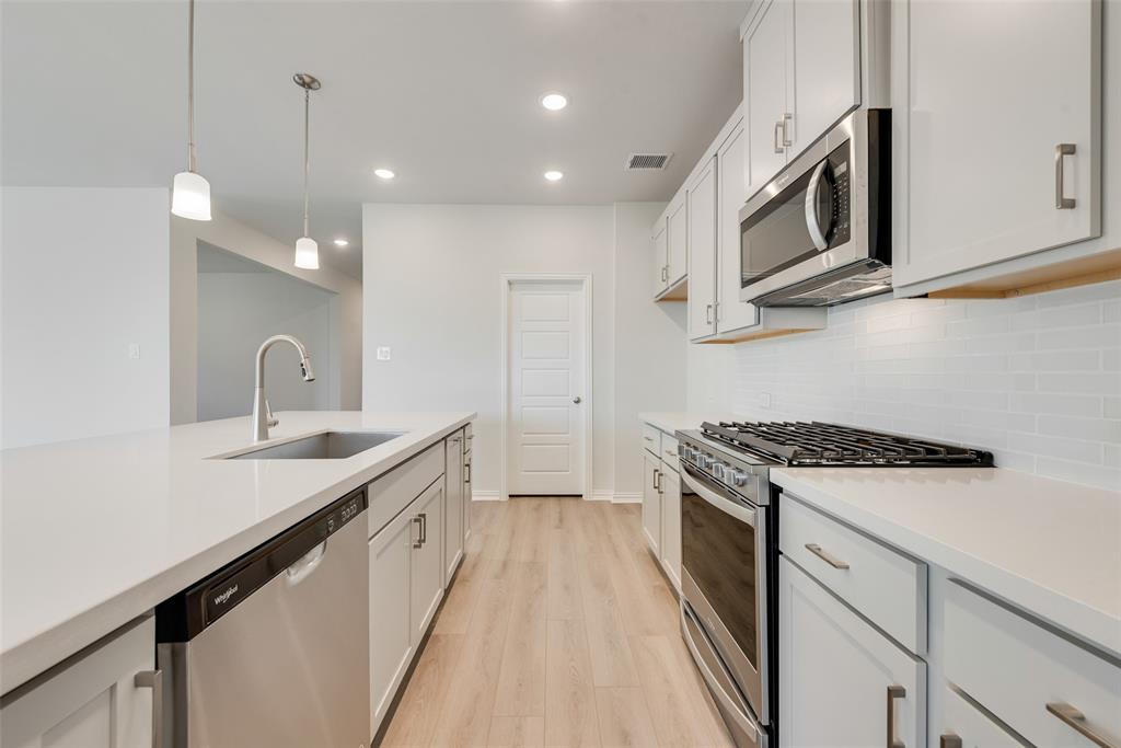 4136 Tarlton Road Little Elm, TX 75068 - Photo 9 of 28 a kitchen with stainless steel appliances granite countertop a sink stove and cabinets