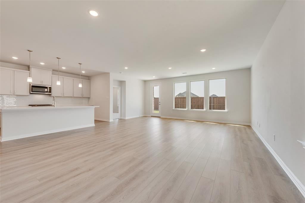 4136 Tarlton Road Little Elm, TX 75068 - Photo 10 of 28 a view of an empty room with wooden floor kitchen appliances and a window