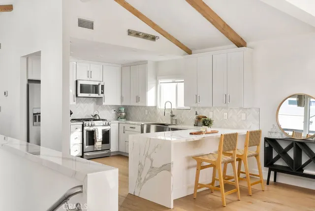 a kitchen with stainless steel appliances kitchen island granite countertop a stove top oven a sink a dining table and chairs with wooden floor