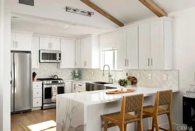 a kitchen with stainless steel appliances granite countertop a stove a sink dishwasher a refrigerator with white cabinets and wooden floor