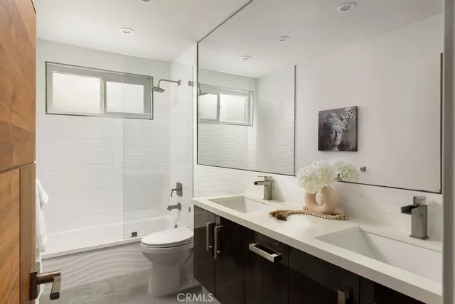a bathroom with a double vanity sink toilet mirror and bathtub