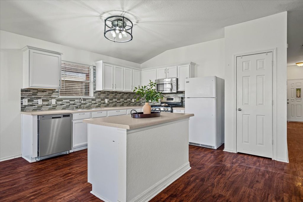 17912 Aleppo Pine Elgin, TX 78621 - Photo 10 of 30 Kitchen featuring vaulted ceiling, appliances with stainless steel finishes, light countertops, white cabinets, and a center island