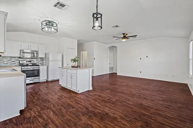 a kitchen with stainless steel appliances a white refrigerator a sink dishwasher a refrigerator and white cabinets with wooden floor