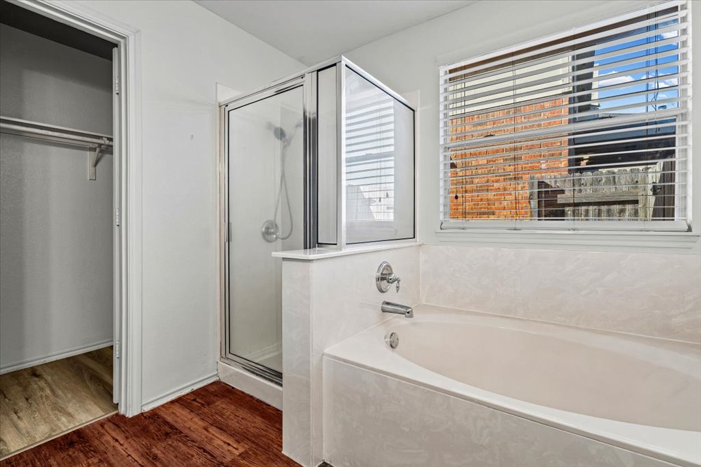 17912 Aleppo Pine Elgin, TX 78621 - Photo 16 of 30 Bathroom featuring a stall shower, dark wood finished floors, a garden tub, and a walk in closet