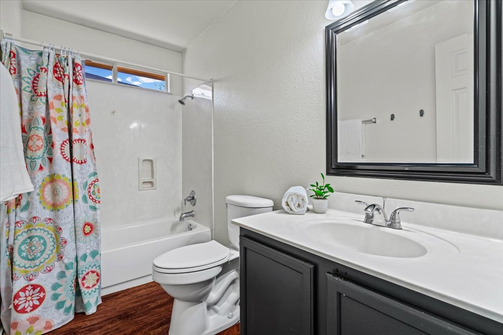 17912 Aleppo Pine Elgin, TX 78621 - Photo 20 of 30 Bathroom with vanity, shower / bath combination with curtain, a textured wall, and dark wood-style flooring