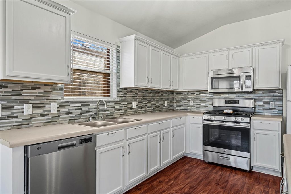 17912 Aleppo Pine Elgin, TX 78621 - Photo 3 of 30 Kitchen with appliances with stainless steel finishes, white cabinets, lofted ceiling, light countertops, and dark wood-style flooring