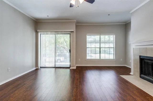 an empty room with wooden floor fireplace and windows