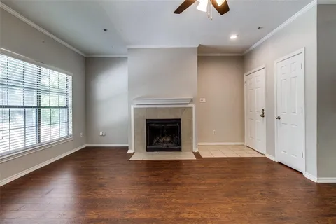 an empty room with wooden floor fireplace and windows