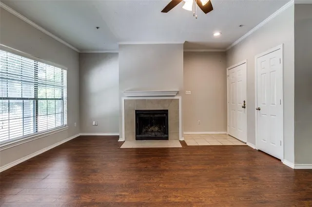 an empty room with wooden floor fireplace and windows