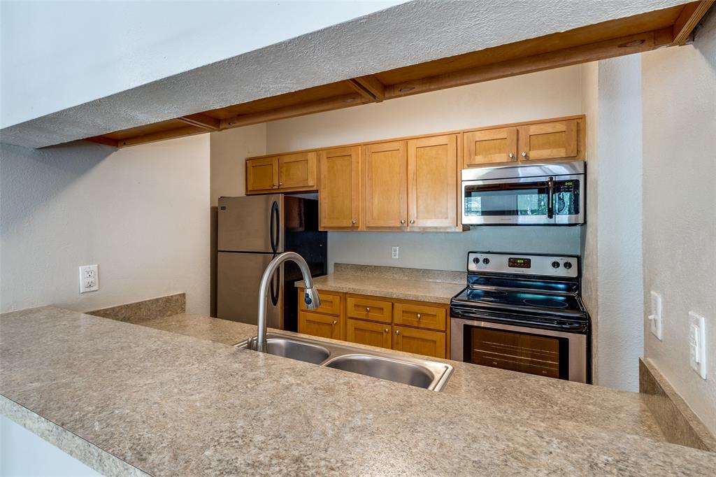 6003 Oram Street, Unit 104 Dallas, TX 75206 - Photo 7 of 23 a kitchen with stainless steel appliances granite countertop a refrigerator and a sink