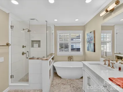 a bathroom with a granite countertop tub sink and mirror