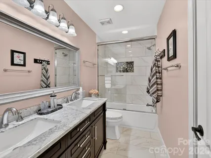 a bathroom with a granite countertop sink a toilet a mirror and shower
