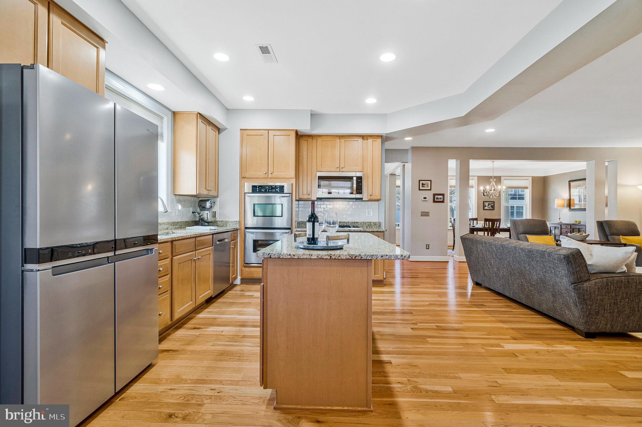 41008 Indigo Place Leesburg, VA 20175 - Photo 16 of 59 a large kitchen with stainless steel appliances granite countertop a refrigerator a sink dishwasher a oven and a dining table with wooden floor