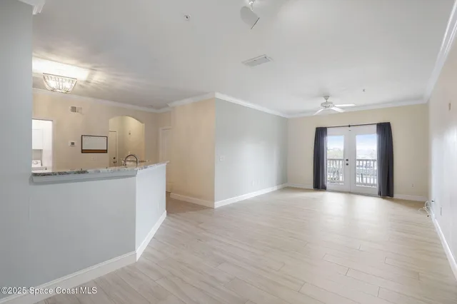 a view of an empty room with a window and a kitchen