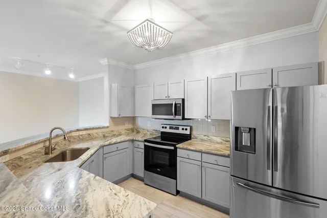 a kitchen with stainless steel appliances a stove refrigerator sink and white cabinets