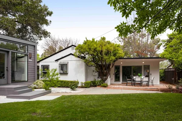 a view of a patio with table and chairs potted plants and large tree