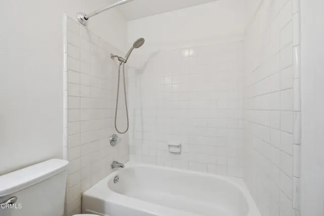 a white bath tub sitting next to a white toilet and a shower