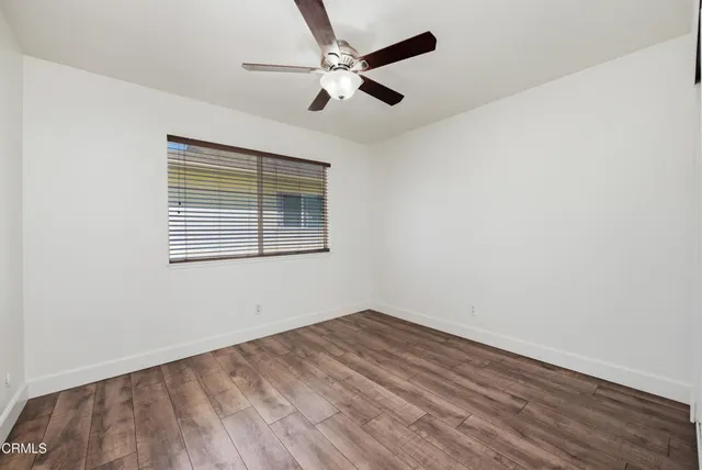 an empty room with a window and a ceiling fan