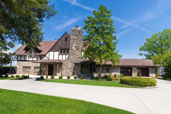 a view of a brick house with a yard plants and large tree